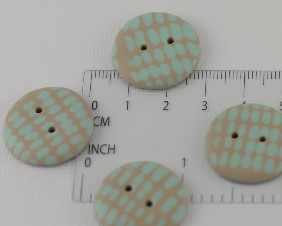 23 mm – 4 vnt. Smėlio rusvos spalvos sagos su mėtinės žalsvos spalvos ornamentu (BT208)